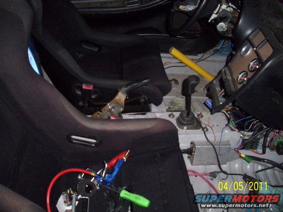 Car interior with racing seats, manual shifter, and exposed wiring. Date stamp 04/05/2011