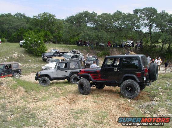 Black Jeep Wrangler with red accents, rear tire visible