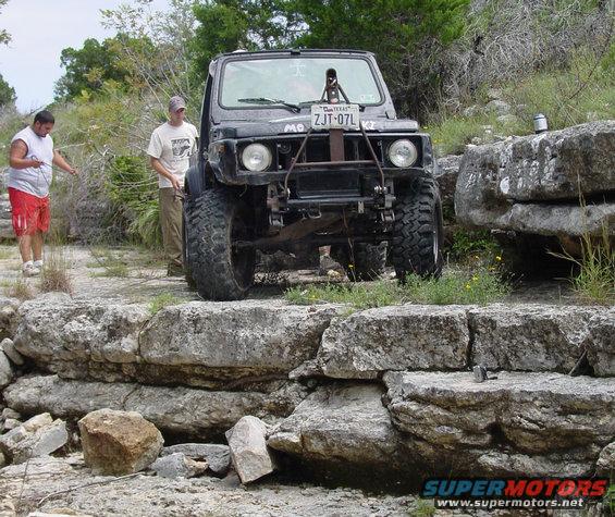 Black off-road SUV with large tires and Texas license plate ZJT-07L on rocky terrain