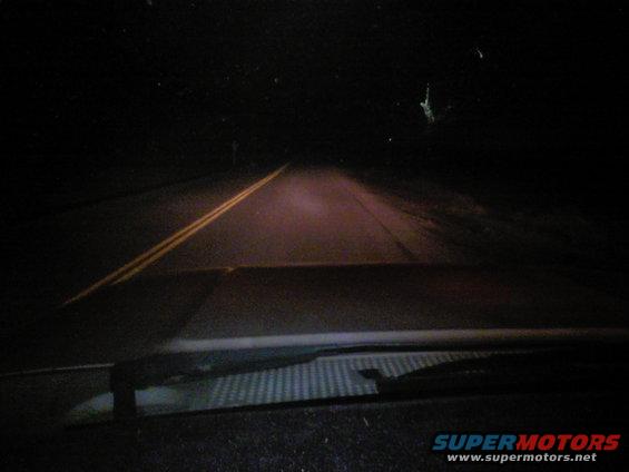 Dark road at night with double yellow lines, seen from inside a vehicle
