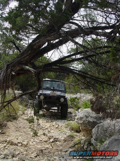 Off-road vehicle with license plate ZJT-97L driving on a rocky, wooded trail