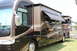 2003 Ford F-350 - Two motorhomes parked on grass, one with its awnings and slide-outs deployed.