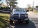 2005 Dodge 2500 - A blue Dodge Ram pickup truck is parked on the street in front of a house. A silver minivan is parked in the yard.
