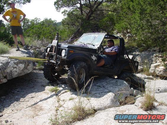 Black off-road vehicle with winch line attached to rock