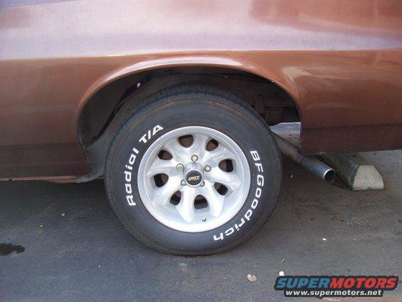 Close-up of a car's rear wheel with BFGoodrich Radial T/A tires and aftermarket wheels. Exhaust pipe visible