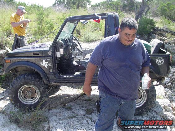 Suzuki Samurai with two men standing nearby on rocky terrain