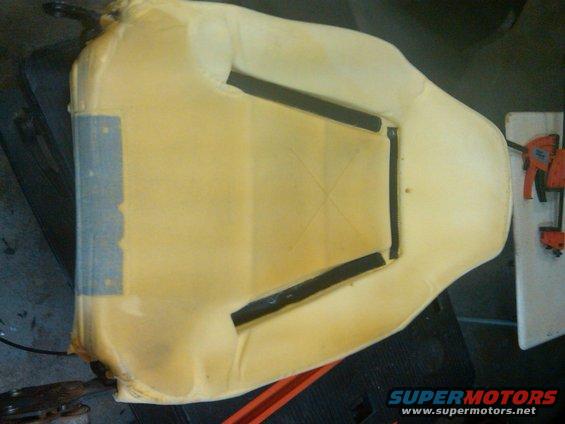 Car seat foam cushion with black heating elements visible, on a dark surface
