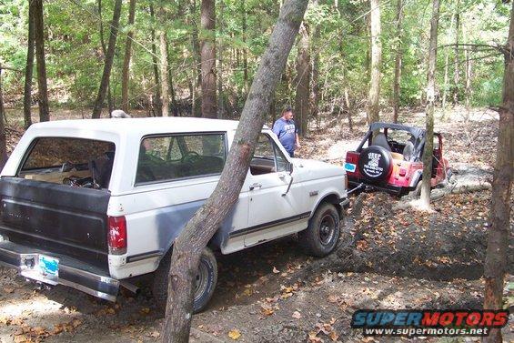 1989 Ford Bronco towing a red Jeep off-road