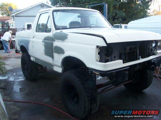 1989 Ford Bronco with primer patches on the body, hood open, and grille removed