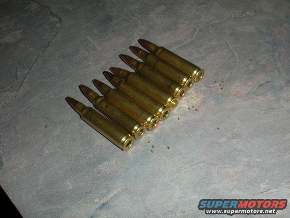 Eight brass cartridges laid out on a textured surface