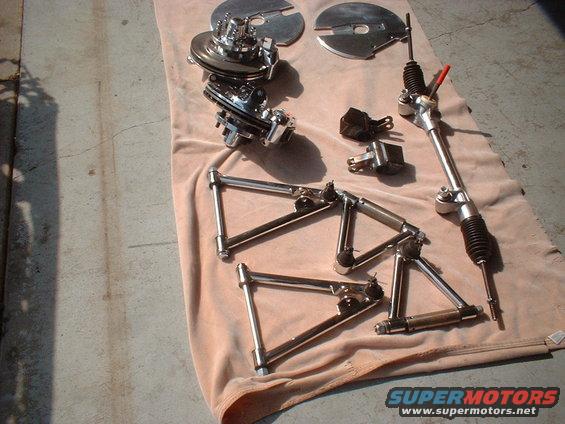 Chrome suspension control arms, brake rotors, and steering rack laid out on a cloth