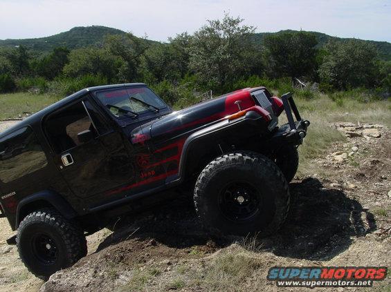 Black Jeep Wrangler with red racing stripes on a dirt trail
