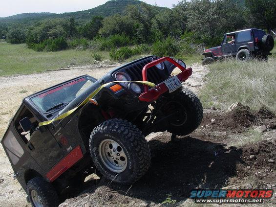 Black Jeep Wrangler on rocky terrain with red bull bar