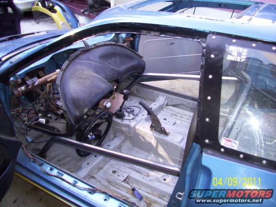 Interior of a stripped-down car with roll cage and exposed wiring