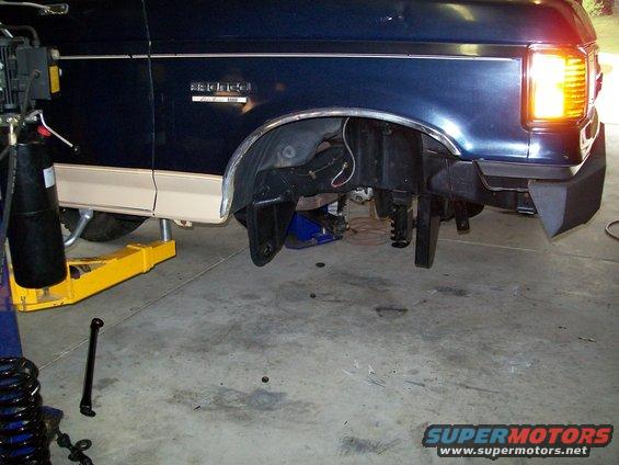 Front driver side wheel well of a 1990 Ford Bronco, lifted for service