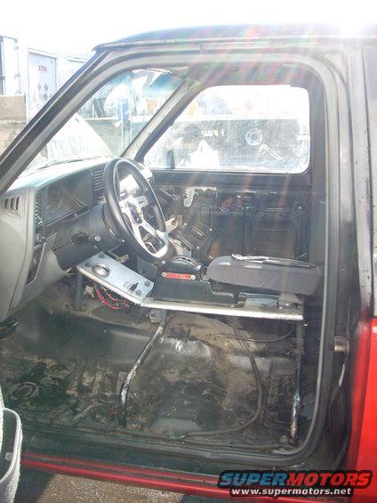 Interior of a truck with door panel removed, aftermarket steering wheel, and exposed wiring