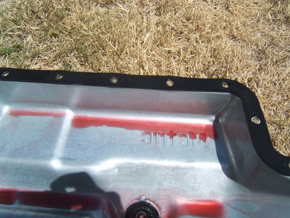 Transmission pan with red fluid and "METALLIC" stamped on it