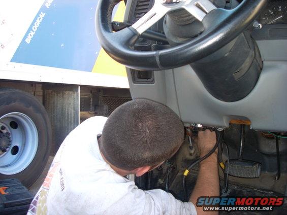Truck interior with a person working on wiring under the steering wheel