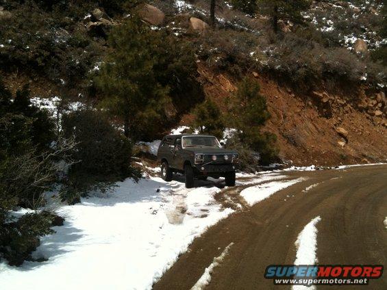 Dark green 1980 Ford Bronco parked on a snowy dirt road