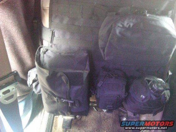 Interior of a vehicle showing a black tactical seat organizer with multiple pouches attached to the seatback