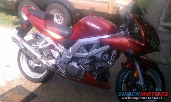 Red 2003 Suzuki SV1000S motorcycle with aftermarket exhaust, parked outdoors