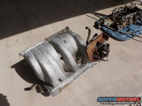Aluminum intake manifold with engine parts on concrete