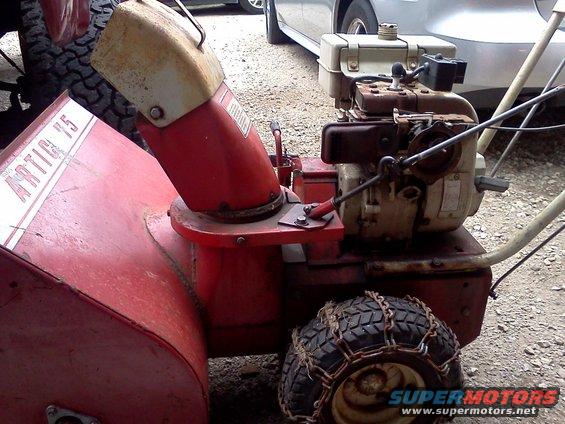 Red snow blower with white lettering reading "ARTIC 15" and a small engine with tire chains