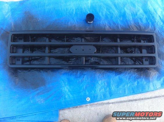 Black Ford Bronco grille with oval emblem mount, sitting on blue tarp