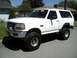 1996 Ford Bronco - White 1996 Ford Bronco with aftermarket wheels and tires, lifted suspension, parked outside.