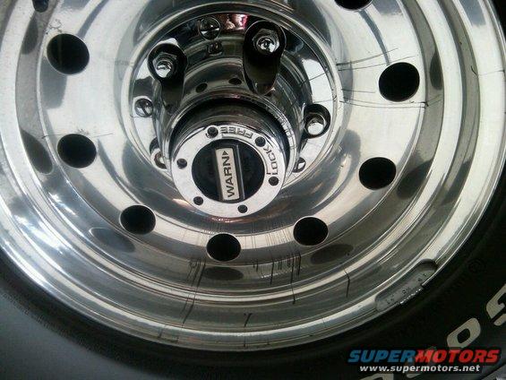 Close-up of a chrome wheel with a Warn locking hub. Tire sidewall visible