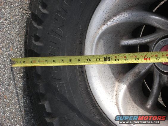 Close-up of a tire and alloy wheel with a yellow measuring tape across it