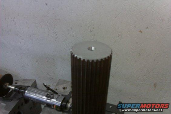 Splined shaft with a hole on top, next to a grinding tool. SUPERMOTORS.NET logo visible