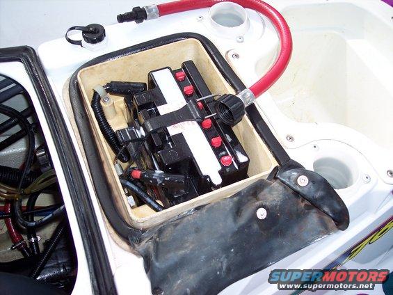 Jet ski battery compartment with a black battery, red hose, and white casing
