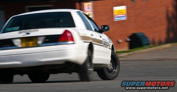 White 2001 Ford Crown Victoria sheriff's car, rear view, driving on asphalt