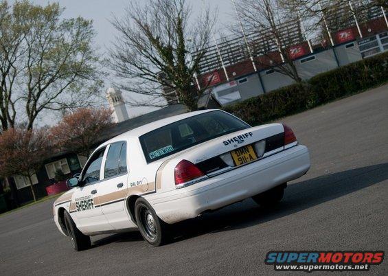 White sheriff car with gold stripe, rear view. License plate reads 'DMH 911-A'