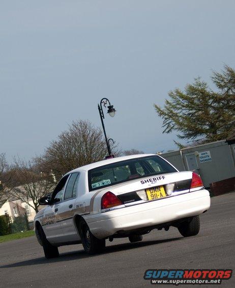 White 2001 Ford Crown Victoria police car, rear view, yellow license plate DMN 911-A