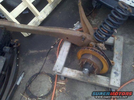 Suspension assembly with coil spring and brake rotor, resting on wooden supports