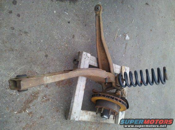 Front suspension assembly with coil spring and brake rotor, resting on wooden blocks