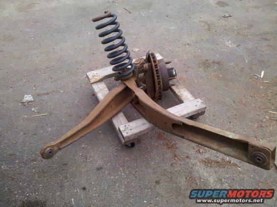 Rusty front suspension assembly with coil spring and brake rotor on a wooden pallet