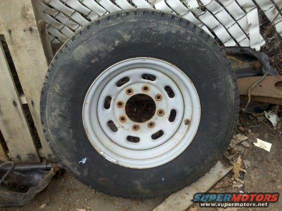Truck wheel with Bridgestone tire, rusty rim, outdoors