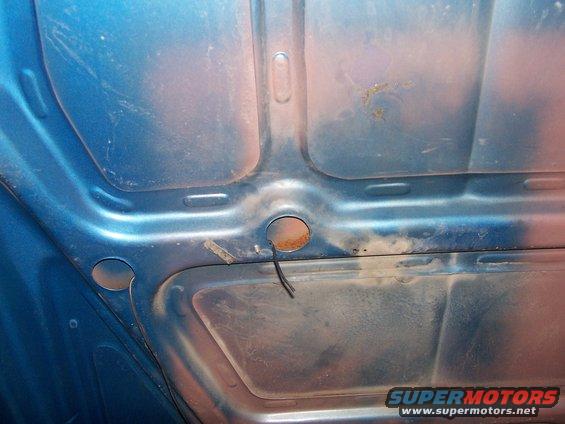Underside of blue hood with rust spots and wiring
