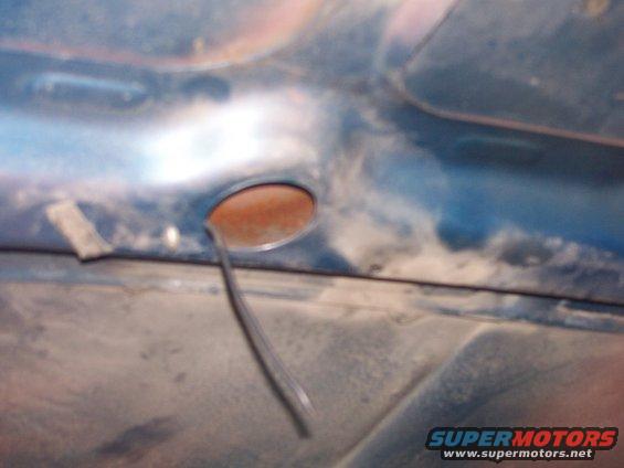 underhood area with a small circular opening and a wire hanging out