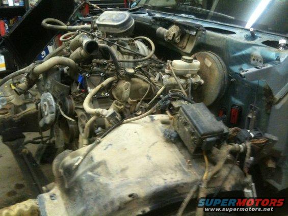 Engine bay of a disassembled vehicle with visible hoses and wiring