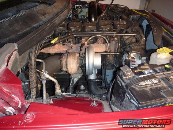 engine bay showing diesel engine, turbocharger, battery, and alternator