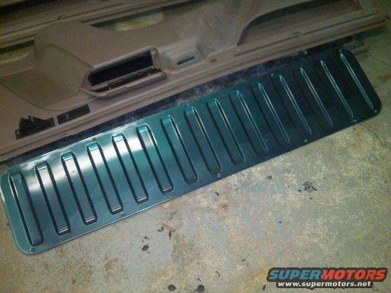 Green metallic trim piece with raised ribs lies on a beige car door panel