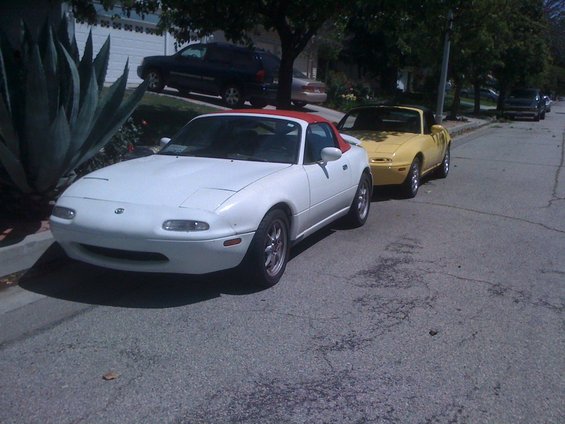 White 1991 Mazda Miata with red convertible top parked on street