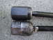 2003 Ford Taurus - Comparison of two tie rod ends, one appearing newer than the other, resting on a textured concrete background.