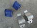 2003 Ford Taurus - Close-up view of automotive suspension parts, including blue rubber bushings and metal brackets, laid out on a concrete surface.