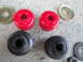 2003 Ford Taurus - A collection of red and black bushings, along with several washers, are laid out on a concrete surface.