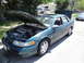 2003 Ford Taurus - Green 2003 Ford Taurus sedan with hood and trunk open, parked on a street.